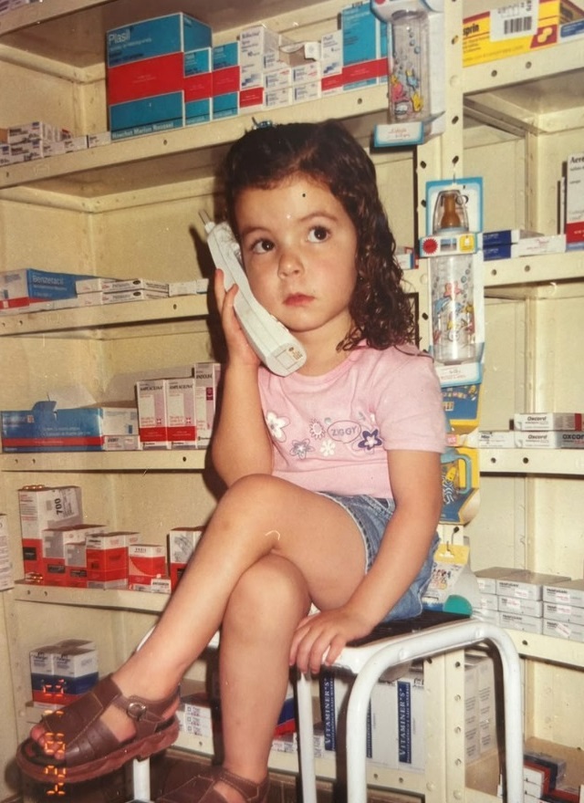 Maria Júlia pequenina atendendo no telefone da farmácia